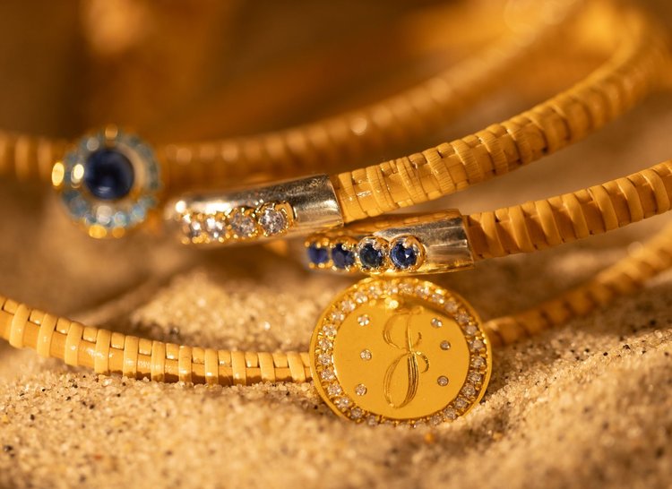 Dark Blue Sapphire Nantucket Basket Bangle in a stack of other bracelets in the sand