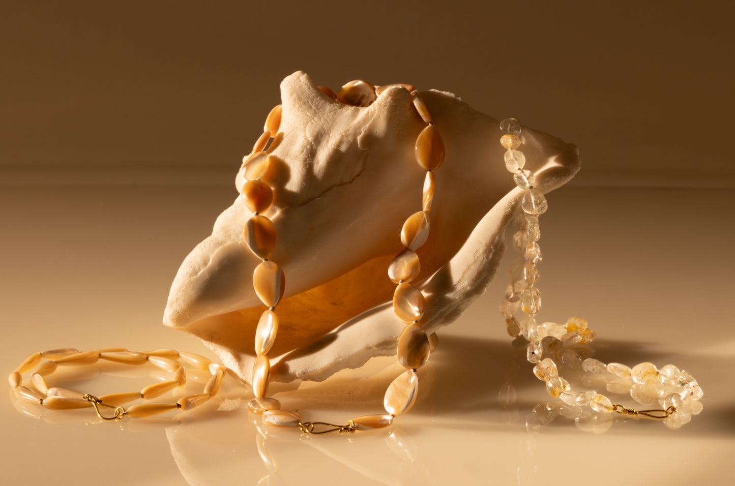 Mother of pearl beaded teardrop necklace draped over a shell