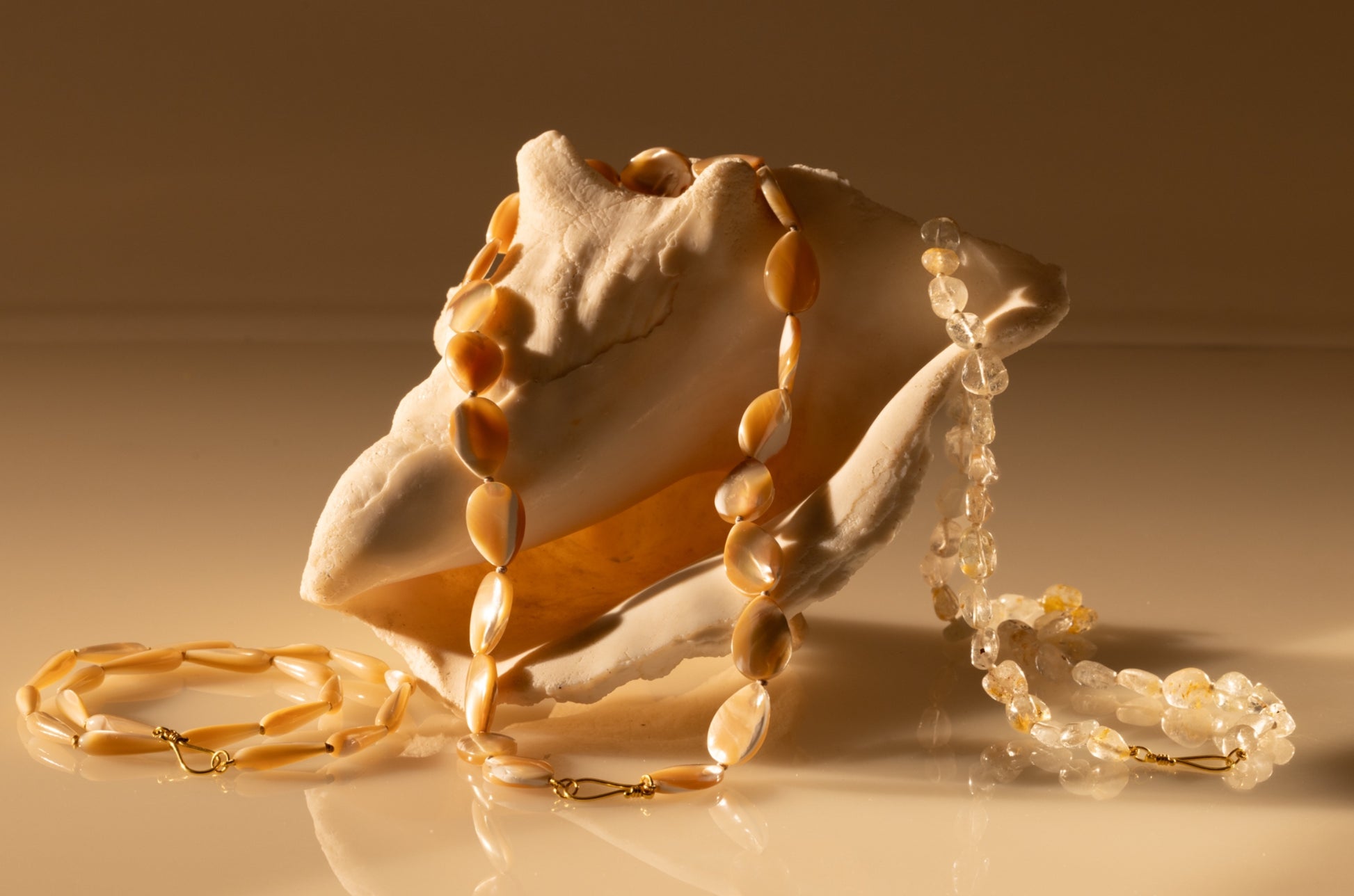 Mother of pearl beaded teardrop necklace draped over a shell