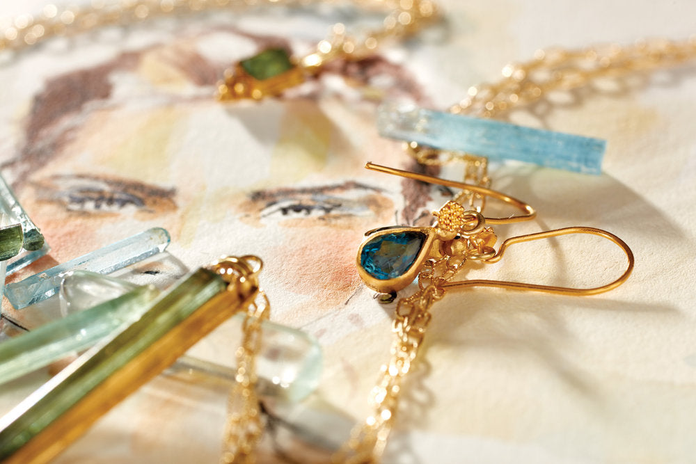 up close photo of blue and green stone jewelry on top of a sketch of a woman