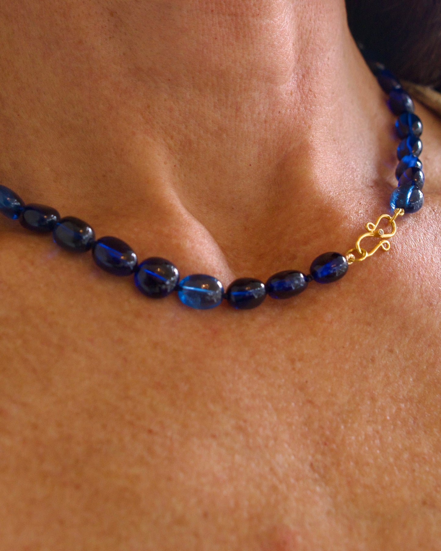 Blue beaded necklace with a gold clasp on a person's neck