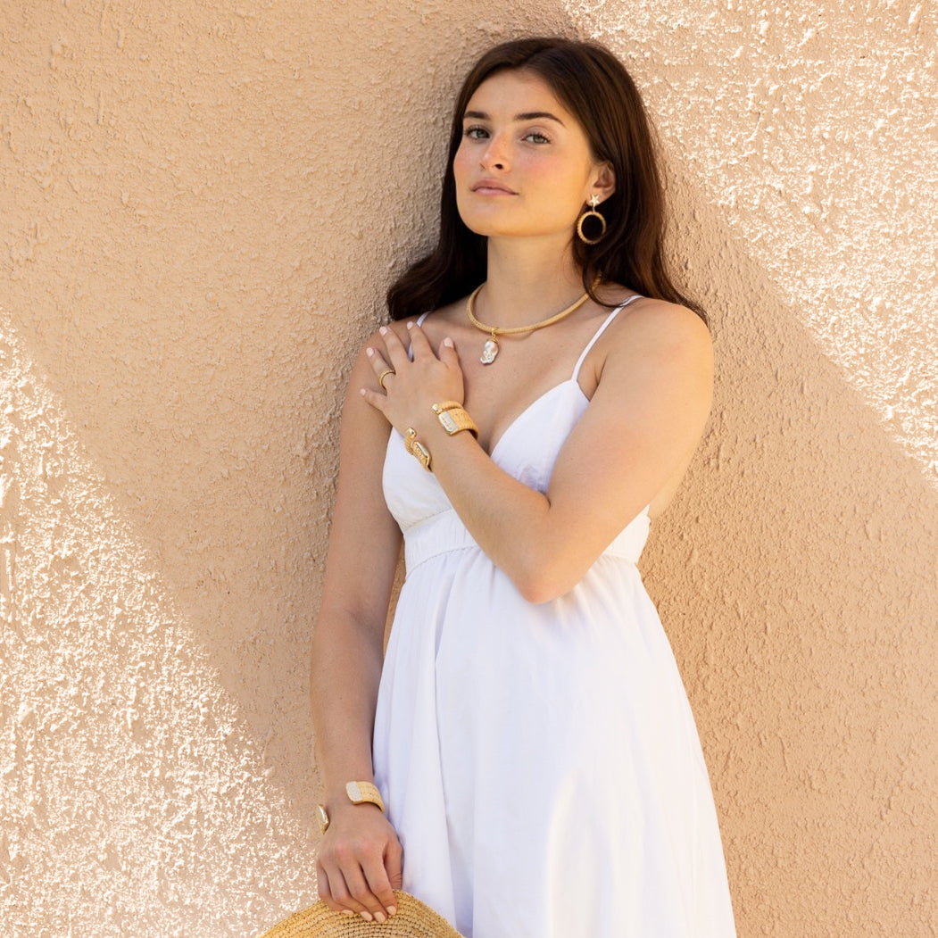 model weaing white dress cuffs, and holding a sunhat