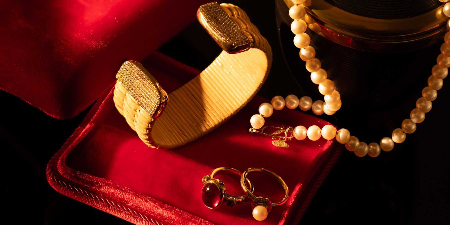 A golden cuff with rings and a pearl necklace