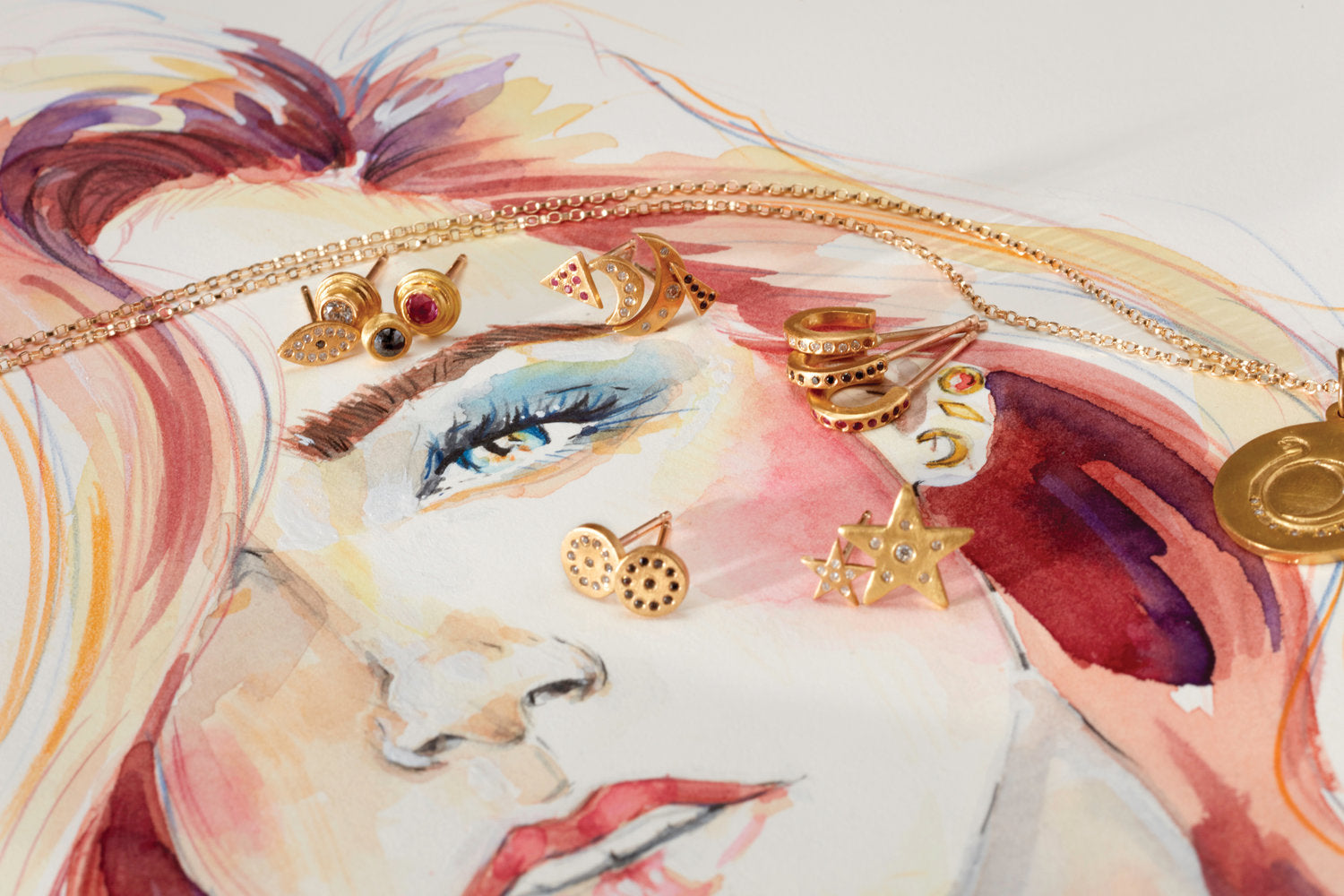 Golden earrings adorned with jewels sitting on top of a sketch of a woman's head