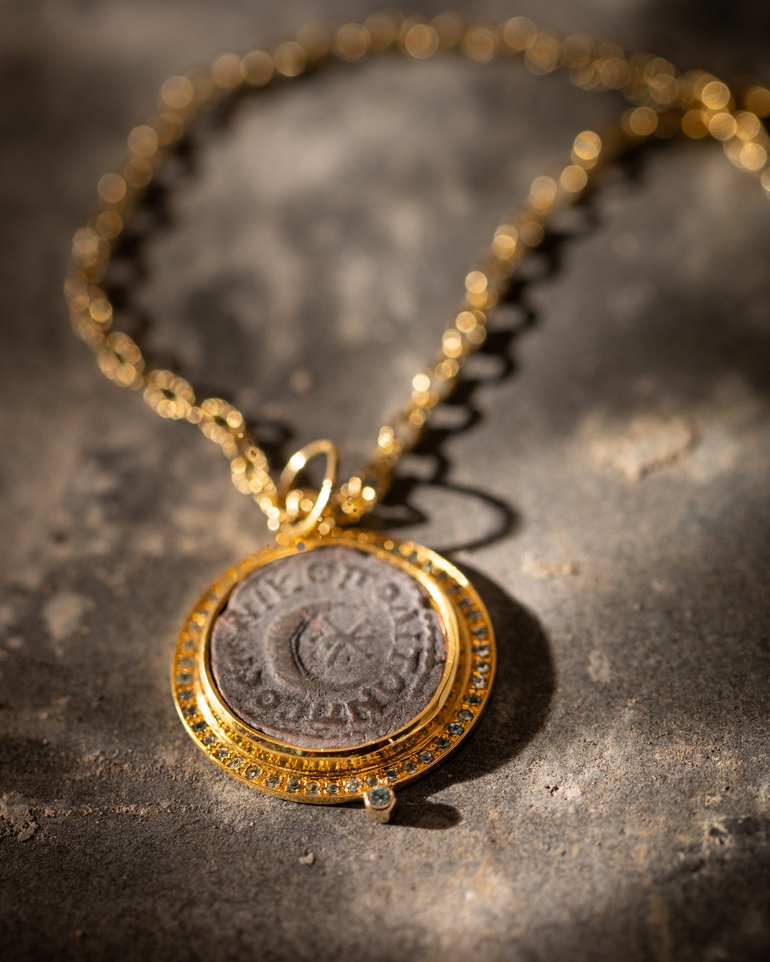  22K gold pendant with a Roman coin depicting a crescent moon and six pointed star dazzles with bright blue zircons