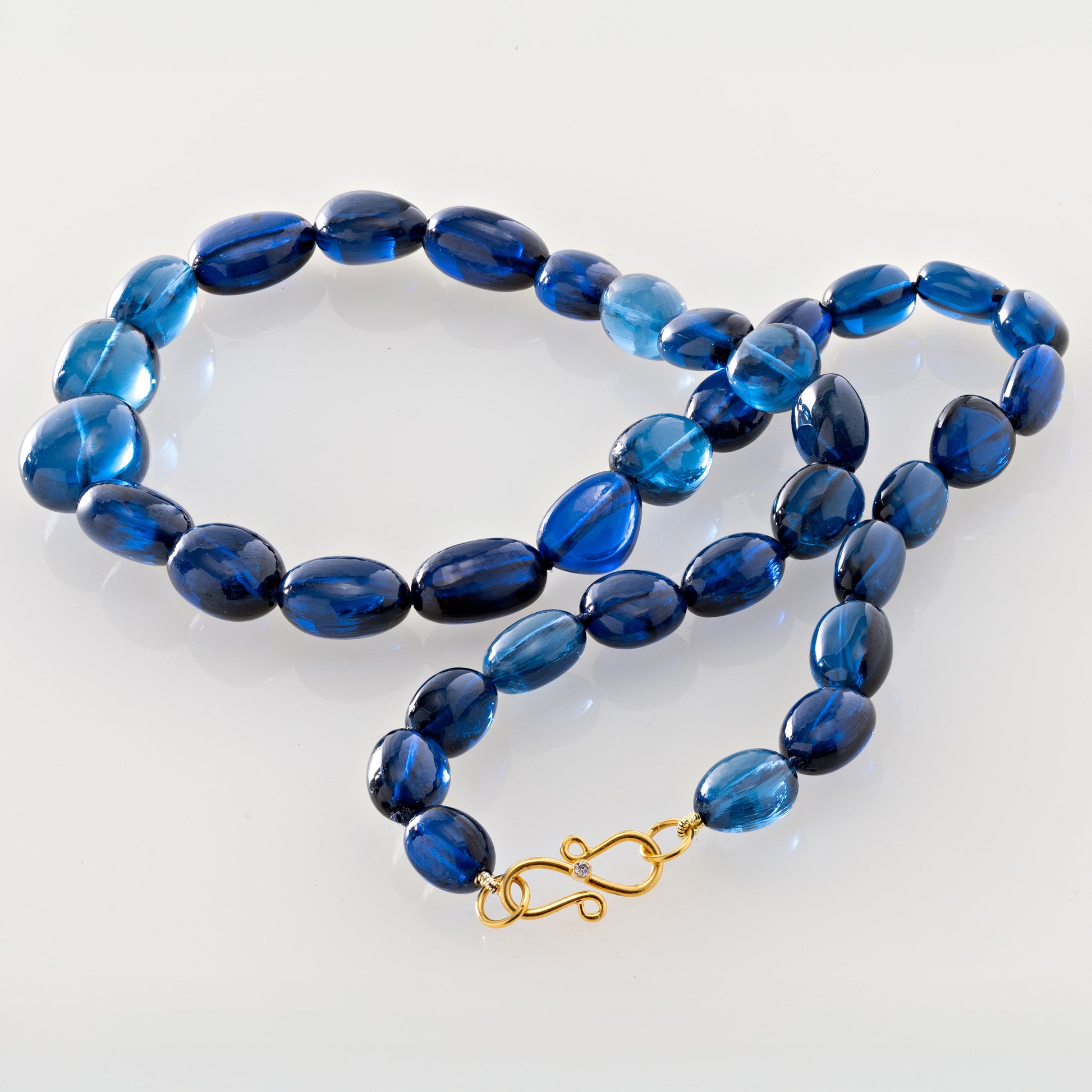 Dark Blue beaded necklace with a gold clasp on a plain background