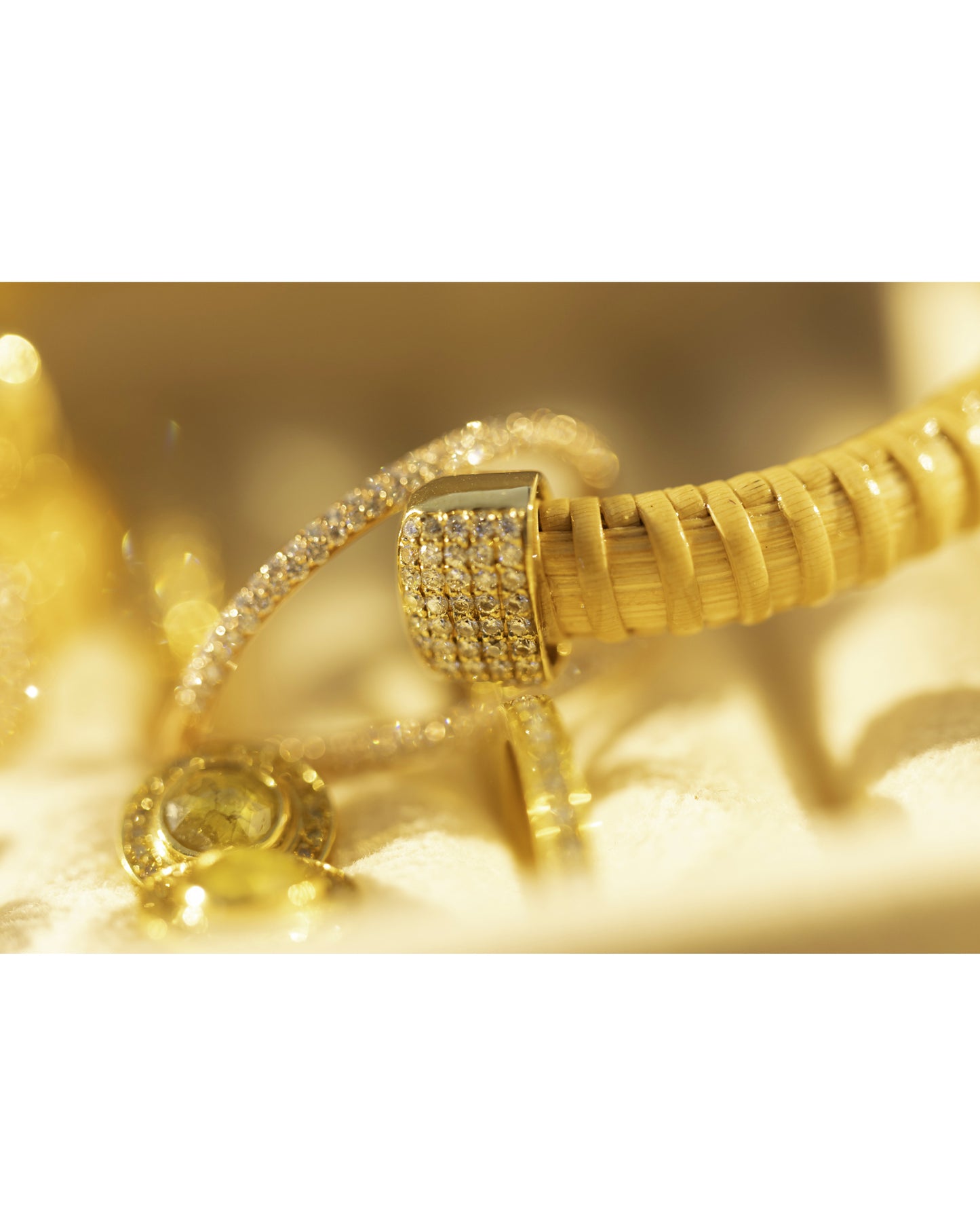 close up of ends of Hyannis Port Nantucket 1/4" Cuff bracelet, handwoven from natural cane and rattan, with yellow gold diamonds sitting with other gold jewelry