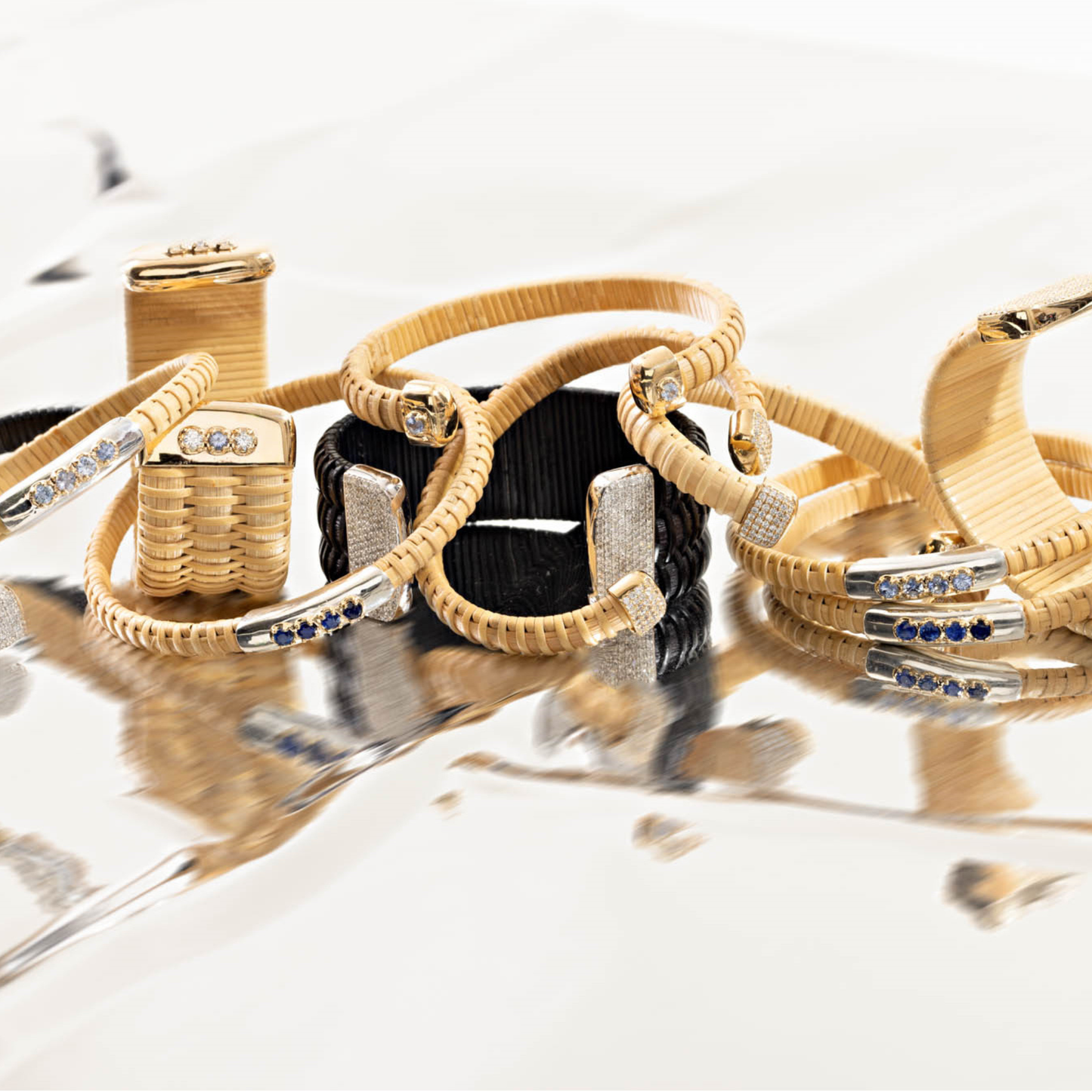 Set of natural and black woven bracelets with diamonds on a reflective surface