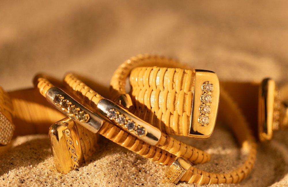 Monomoy Sunrise Nantucket Lightship Basket 1" Cuff, handwoven from natural cane and rattan, with Gold and Diamonds in stack of other bracelets in the sand