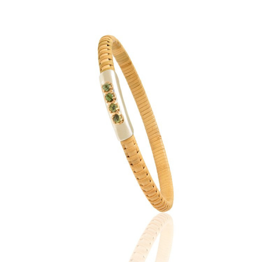 Natural rattan woven bracelet with gold cap and green stones on a blank background