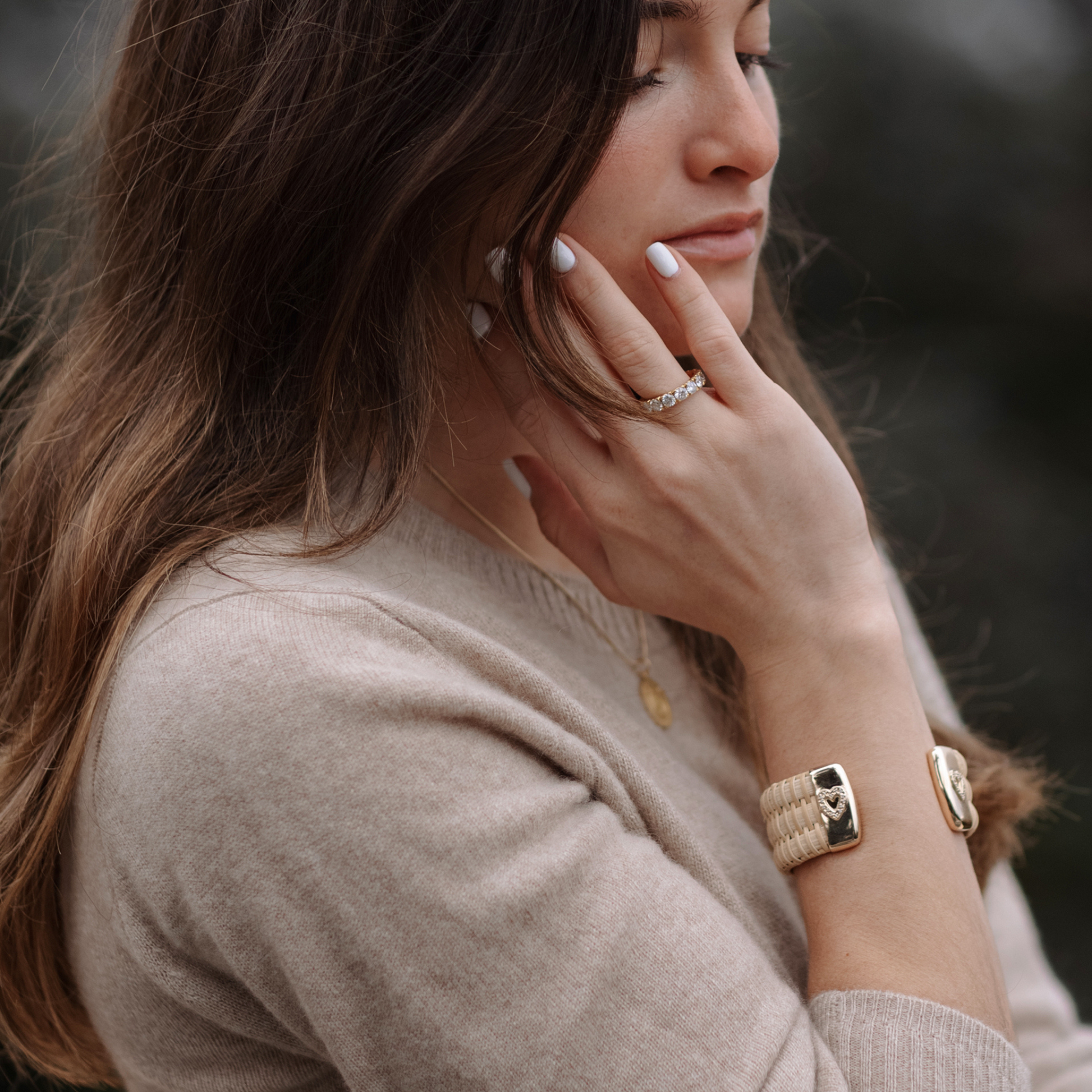 female wearing woven cuff bracelet with gold caps and heart in diamonds