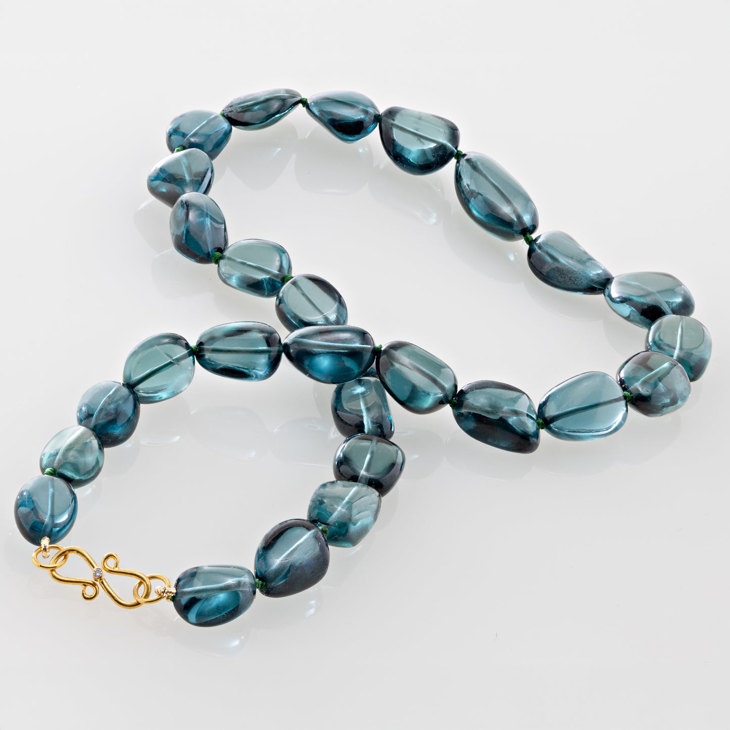 Blue beaded necklace with a gold clasp on a plain background