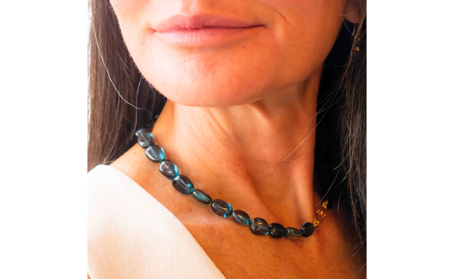 Close up of a woman wearing necklace with blue beads and gold clasp