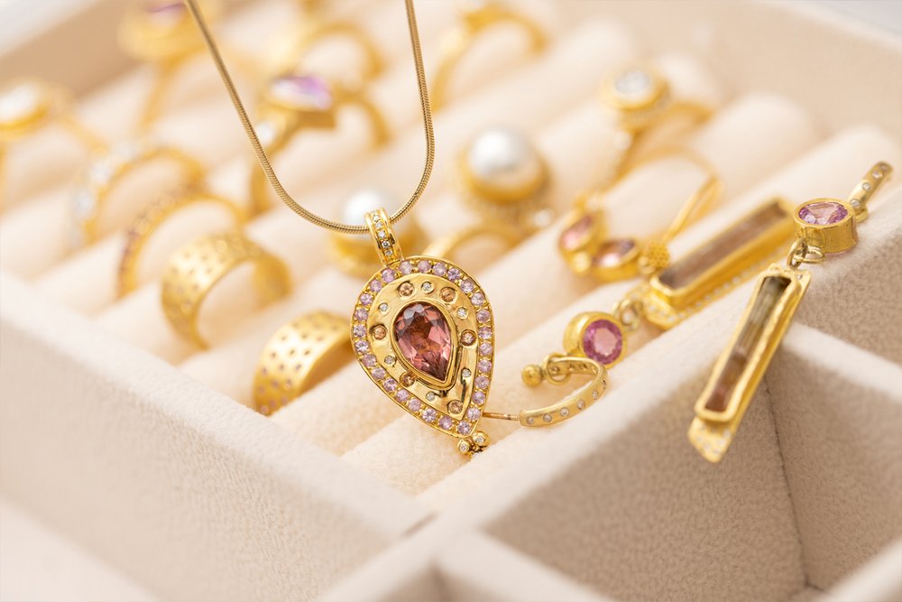 Dawn Pendant laying across other pieces of gold jewlery