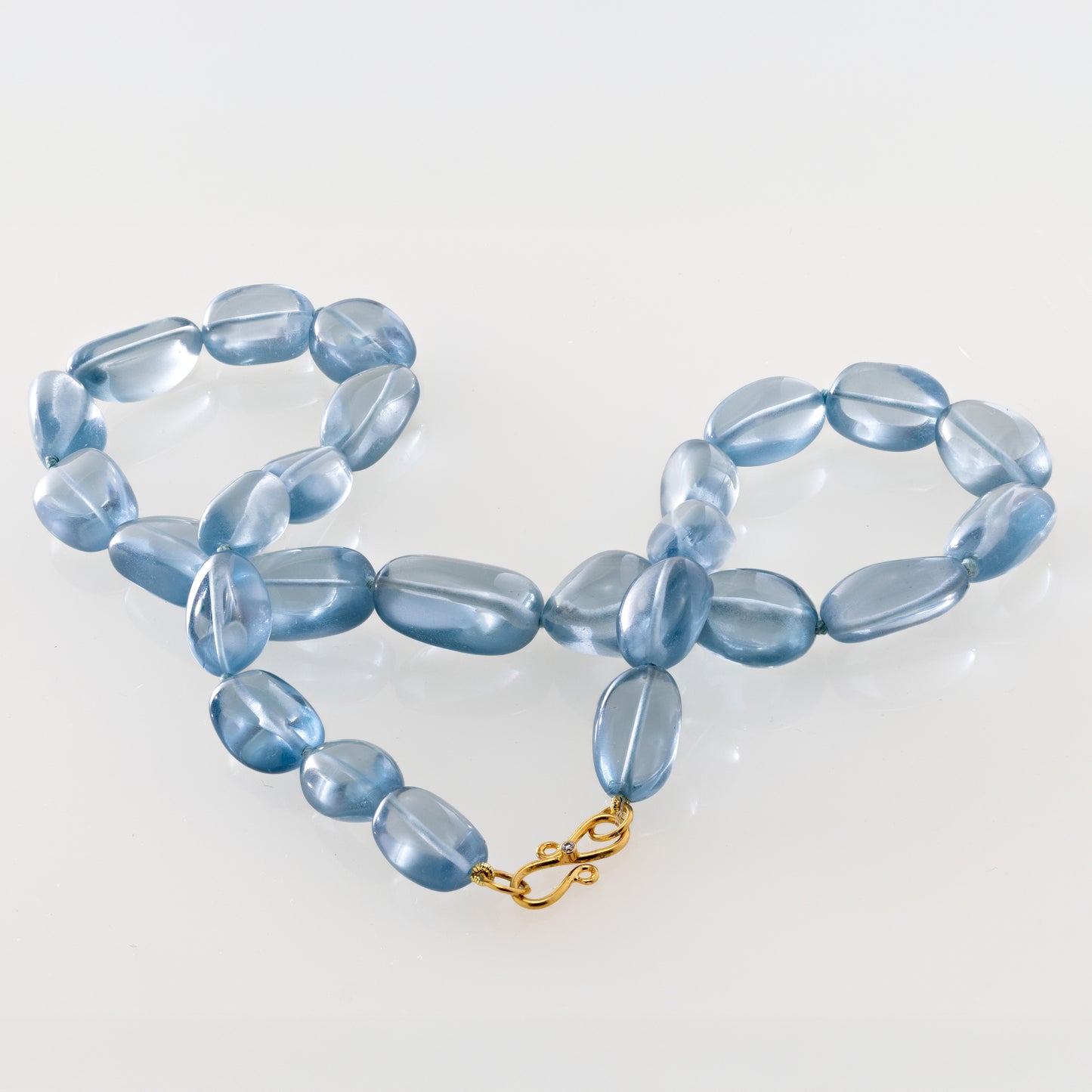 Light Blue beaded necklace with a gold clasp on a plain background