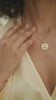 Woman waring aquamarine stone 22k gold pendant and lightweight cashmere wrap in yellow