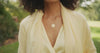 woman wearing gold pendant with aquamarine stone also wearing lightweight yellow wrap shawl