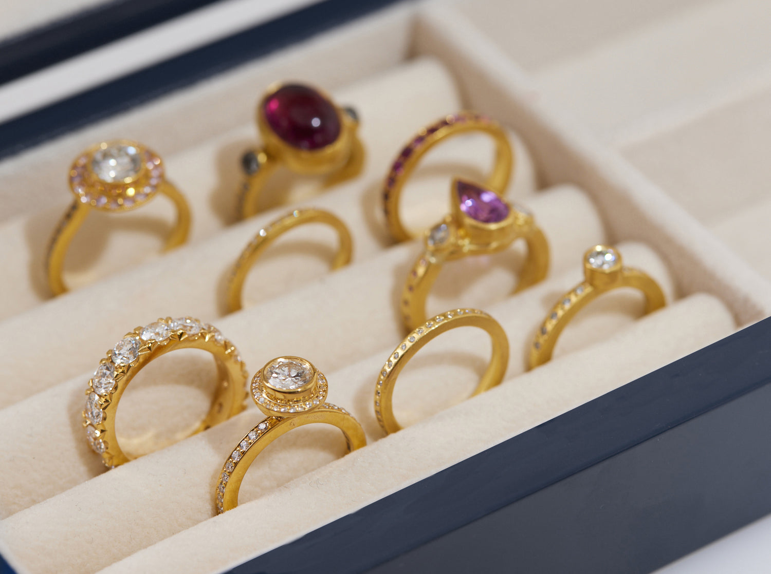 several gold rings with different colored stones in a ring box